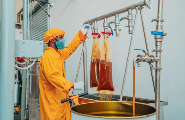 Worker in protective clothing operating filtration equipment at a processing plant