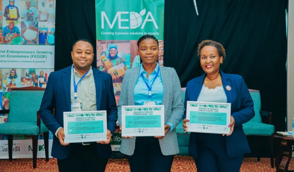 Three participants holding certificates in front of event branding