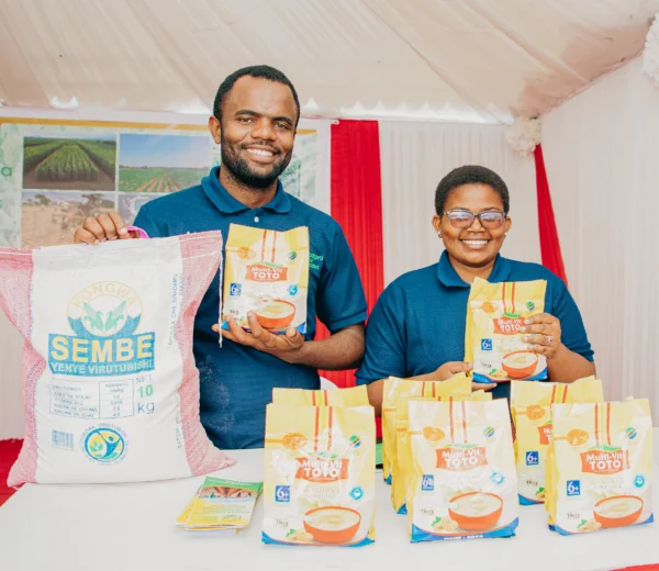 Two exhibitors holding branded packaged food products at a trade event