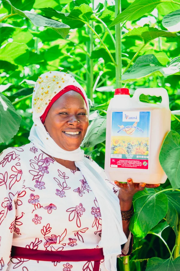 Woman in patterned headwrap holding a branded container of cooking oil
